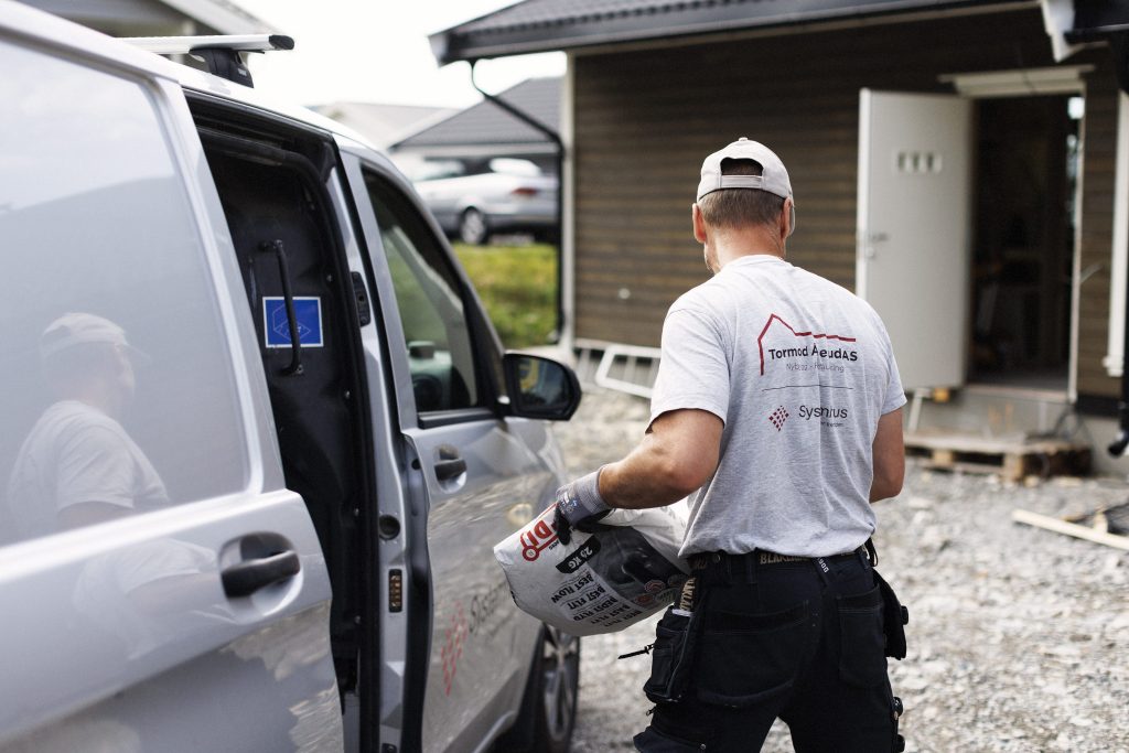 bildet viser en mann som løfter ut en sekk fra en bil
